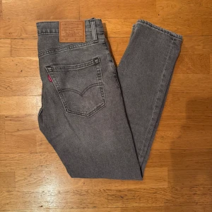 Levi's 502 grå jeans W31 L32 - Snygga grå Levi's 502 jeans med klassisk femficksdesign och läderpatch bak. Jeansen har en slim/rak passform och är tillverkade i premium denimtyg. Perfekt för dig som gillar en stilren look med lite edge.