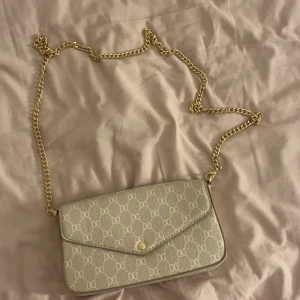 Beige kuvertväska med kedja från DKNY - Snygg beige kuvertväska  