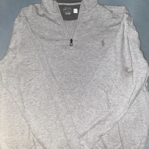 Grå half zip tröja Polo Ralph Lauren - Snygg grå tröja från Polo Ralph Lauren med klassisk broderad logga på bröstet. Modellen har en halv dragkedja vid halsen och är tillverkad i mjuk bomull. Perfekt för lager-på-lager och chill stil. Tröjan e riktig men passar inte det därför jag säljer priset kan förhandlas ny pris 2300