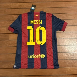 FC Barcelona Messi #10 Nike tröja M - Säljer en officiell FC Barcelona matchtröja med Messi #10 på ryggen. Tröjan är kortärmad, tillverkad i Dri-Fit material och har breda marinblå och röda ränder. Tryck med Qatar Airways, UNICEF och Intel Inside. Champions League-märke på ärmen och klubbmärke på bröstet.