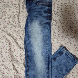 Blå jeans från WT02, storlek 30/30 - Snygga blå jeans från WT02 i storlek 30/30. De har en klassisk femficksdesign, gul kontrastsöm och dragkedja i gylfen. Jeansen har en tvättad look med ljusare partier framtill och är tillverkade i slitstarkt denimtyg.