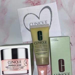 Clinique Moisture Surge & Lotion Kit - Kit med Clinique Moisture Surge 100H auto-replenishing hydrator i ljusrosa burk, Dramatically Different Moisturizing Lotion+ i gul tub och Moisture Surge Sheertint Hydrator SPF 25. Perfekt för återfuktning och lätt täckning. Kommer i originalförpackning och med färgglad necessär.
