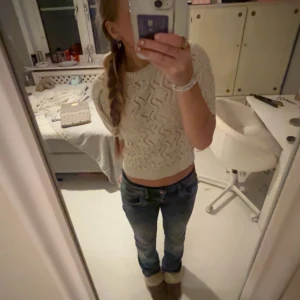 Vit stickad croppad topp - Säljer en vit stickad croppad topp med korta ärmar och snyggt hålmönster. Toppen har rund halsringning och ribbad kant nedtill, perfekt att styla med jeans för en chill look.