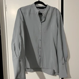 Ljusgrå skjorta från Zara XS - Stilig, lagom lätt och lagom oversized skjorta som funkar för formella event, kontor, till fashion-intresserade men även vardagligt. Clean och minimalistisk look. Färgen är ljusgrå med en väldigt svag blå touch. Knappar ända upp till nackden. En liten skavank på baksidan somd et syns på bilden.
