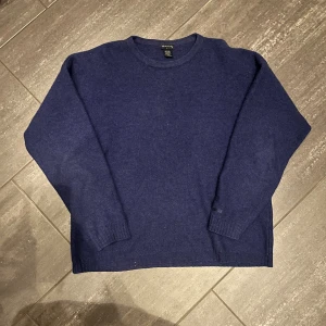 Mörkblå stickad tröja från GANT - Mörkblå stickad tröja från GANT i storlek L. Tröjan har rund hals och långa ärmar. Enkel och klassisk design som funkar till många olika stilar. Perfekt för dig som gillar en chill och stilren look. Beklagar för dålig bild (3) ska åtgärda det vid tillfälle.