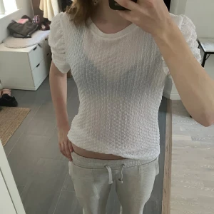 Vit blus med puffärm från Vila XS - Säljer en vit blus från Vila i storlek XS med puffiga korta ärmar och ett snyggt strukturerat tyg. Blusen har rund hals och är lätt transparent, perfekt för dig som gillar en fräsch och trendig look. Passar dig som vill ha något som sticker ut lite extra.