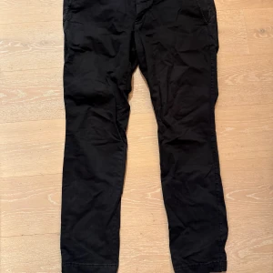 Mörka skinny byxor från GAP - Mörka skinny byxor från GAP i storlek 38x32. Byxorna har en smal passform och är tillverkade i mjuk bomull. Klassisk design med fickor fram och bak, perfekt för en clean och stilren look.