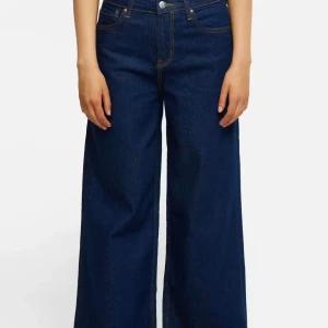 Mörkblå wide jeans - Säljer ett par mörkblå jeans med riktigt breda ben och hög midja. Klassisk femficksmodell med kontrastsömmar och raka bakfickor. 