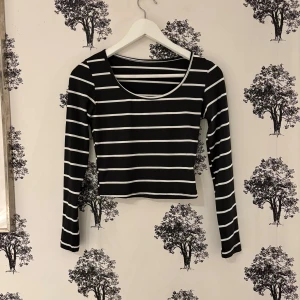 Svartvit randig långärmad topp från SHEIN - Svart långärmad topp från SHEIN med vita horisontella ränder. Croppad modell med rundad halsringning och slim passform. Tillverkad i mjuk och stretchig polyester som sitter skönt mot kroppen. Perfekt för dig som gillar stilrena och trendiga plagg.