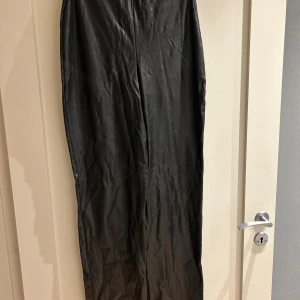 Svarta skinnbyxor från NLY One - Säljer ett par svarta skinnbyxor från NLY One i storlek S. Byxorna har en hög midja och raka ben med en snygg, stilren look. Materialet är syntetiskt skinn som ger en cool vibe och passar perfekt till en trendig outfit.