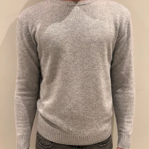 Ljusgrå stickad tröja John Henric - En stilren ljusgrå stickad tröja från John Henric. Tröjan har rund halsringning, ribbade muddar och är tillverkad i mjukt material som passar perfekt till lager-på-lager. Enkel och clean look som funkar till allt.