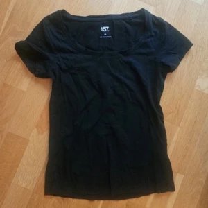 Svart kortärmad topp från 157 - En enkel svart topp från 157 med rund halsringning och korta ärmar. Tillverkad i mjuk bomull som är skön mot huden. Perfekt att matcha med jeans eller kjol för en clean och stilren look.