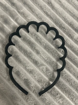 Svart vågigt diadem ny - Snyggt svart diadem med vågig design som ger en cool och unik look. Tillverkat i blank plast och passar perfekt för att hålla håret på plats samtidigt som det blir en statement-accessoar. Enkel att matcha med olika stilar och outfits.