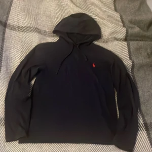 Mörkblå hoodie från Ralph Lauren - Säljer en stilren mörkblå hoodie från Ralph Lauren med det klassiska röda logotypbroderiet på bröstet. Tröjan har en bekväm huva med dragsko och långa ärmar. Perfekt för en avslappnad look. Har några fläckar som kan ses på bilderna. Pris är diskuterbart.