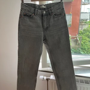 Grå raka lågmidjade petite jeans från Gina tricot - Snygga grå jeans från Gina Tticot med klassisk femficksdesign och raka ben. Jeansen har låg midja, silverfärgade knappar och detaljer i koppar vid fickorna. Materialet är robust denim i bomull som ger en cool vintagekänsla. Jeansen är i petite 32.