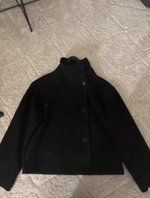 Svart kappa med hög krage - Jackan är från Gina och i storlek XS. Priset kan diskuteras!!!