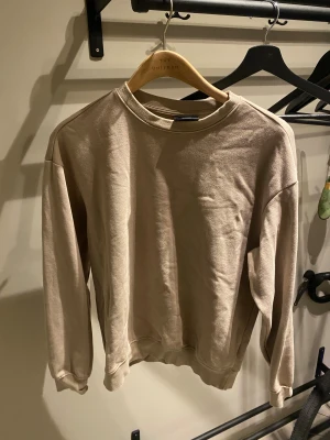 Beige sweatshirt från H&M  - En beige sweatshirt från H&M i relaxed fit, storlek XS. Tröjan har rund hals, ribbade muddar och är långärmad. Perfekt för chill dagar och enkel att matcha med jeans eller joggers. Materialet är mjukt och känns skönt mot huden.