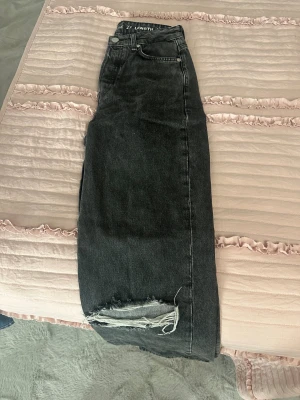 Svarta wide jeans med slitna knän - Snygga svarta jeans från H&M i wide fit-modell med hög midja. Jeansen har slitna detaljer vid båda knäna för en cool look. Klassisk femficksdesign och tillverkade i kraftigt denimtyg. Perfekta för dig som gillar en avslappnad och trendig stil.