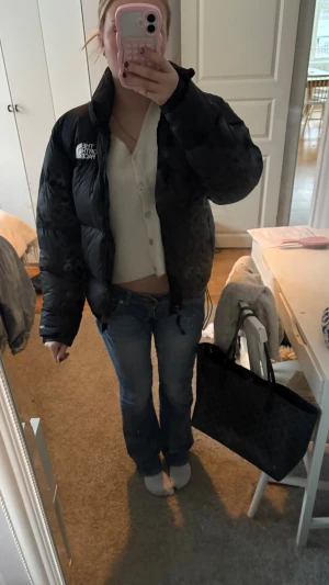 Svart pufferjacka från The North Face - Säljer en svart pufferjacka från The North Face med hög krage och synligt logotryck på bröstet. Jackan har lång ärm, dragkedja framtill och är tillverkad i slitstark polyester. Perfekt för kalla dagar och har en riktigt chill oversized vibe.