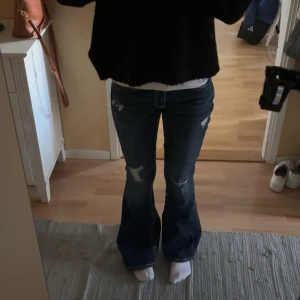 Mörkblå bootcut jeans med slitningar från Gina - Snygga mörkblå bootcut jeans från Gina 14+ med slitna detaljer och markerade sömmar. Jeansen har låg midja och coola broderade bakfickor. Materialet är klassisk denim och passformen är loose nertill med utsvängda ben. Lite för långa på mig som är 162 cm. I storlek S och är just nu slutsåld på Gina. Helt nya, bara använda en gång ❤️