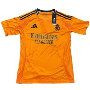 Real Madrid Vini Jr. orange matchtröja - Snygg orange Real Madrid fotbollströja från Adidas med Vini Jr. och nummer 7 på ryggen. Tröjan har svarta detaljer, klubbmärke på bröstet och Aeroready-material som andas. Klassisk kortärmad modell med tryckta ränder på axlarna.