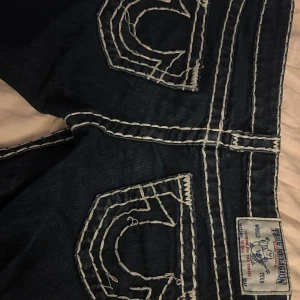 True Religion bootcut jeans mörkblå - Mörkblå jeans från True Religion med tydliga vita kontrastsömmar. Omsyda ifrån skinny till bootcut! med svart tyg❤️