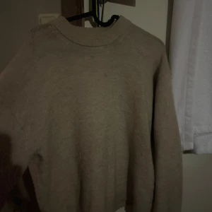 Beige stickad tröja från H&M - Mysig beige stickad tröja från H&M med rund halsringning och långa ärmar. Perfekt för lager-på-lager och chill dagar. Enkel och stilren design som passar till det mesta.