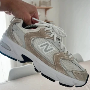 New Balance 530 sneakers beige/vit - Snygga New Balance 530 sneakers i beige och vitt med mesh och mockadetaljer. Skorna har en chunky vit sula med svarta detaljer undertill och klassisk snörning. Ikoniskt N på sidan och sportig vibe som passar till många outfits. Har en liten fläck som syns på sista bilden 