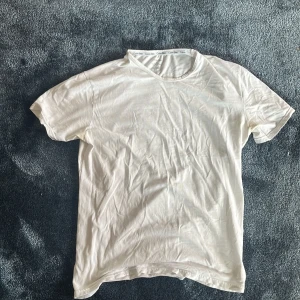 Vit t-shirt från Calvin Klein - Snygg vit t-shirt från Calvin Klein med klassisk rund hals och diskret logga på insidan av kragen. Tillverkad i mjuk bomull som känns skön mot huden. Perfekt för dig som gillar stilrena och enkla plagg med premiumkänsla.