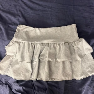 Grå volang mini kjol  - Superfin grå minikjol ifrån SHEIN i storlek XS med insatta shorts i kjolen, perfekt med short i. 