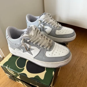 BAPE STA sneakers vit/grå patent - Säljer ett par BAPE STA sneakers i vit och ljusgrå patentläder. Klassisk siluett med stjärnlogo på sidan, perforerad tå och vita snören med metalltips. Kommer med originalkartong i camomönster. Riktigt clean och stilren modell för dig som gillar streetwear.