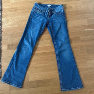Blå bootcut jeans från Gina Tricot - Snygga blå jeans från Gina Tricot i modell med bootcut. Jeansen har låg midja, klassiska fem fickor och dubbla knappar i linningen. Tillverkade i mjukt denimtyg med lite stretch för extra komfort. Perfekta för dig som gillar en retro vibe. Tyvärr ingen bild med jeansen på då jag ej får på mig de längre. Men sitter såå fint på! 💓
