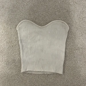 Beige ribbad tubtopp - Snygg off white tubtopp med ribbad struktur och hjärtformad överkant. Toppen är strapless och har en croppad passform som sitter tight mot kroppen.💗 