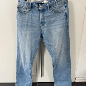 Jack & Jones Loose/Chris ljusblå jeans - Ljusblå jeans från Jack & Jones i modellen Loose/Chris. Klassisk femficksdesign, raka ben och lös passform för en avslappnad vibe. Tillverkade i bomullsdenim med snygga slitningar och ljus tvätt. Perfekta för dig som gillar en loose fit och streetstil.