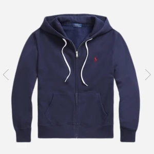 Mörkblå ziphoodie från Ralph Lauren - Snygg mörkblå hoodie från Ralph Lauren med dragkedja och vit snörning i huvan. Klassisk röd logga broderad på bröstet och två stora fickor framtill. Detta är den kända modellen som många har, nypris betalade jag 1850kr på rea. Den är i väldigt bra skick och inget slitage alls.