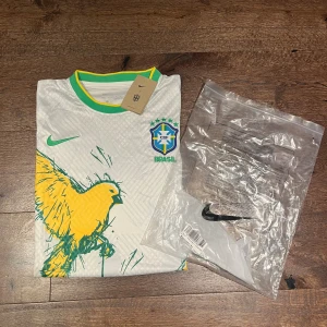 Brasilien koncept tröja - Säljer en Basilian koncept tröja med vit bas och en gul tropisk fågel på. Perfekt när du vill ha på dig en tröja som är enkel och clean. 