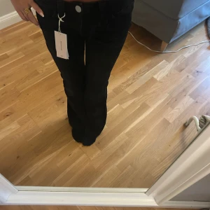 Svarta bootcut jeans med nitar - Svarta jeans från Gina 14+ i storlek 164 med bootcut-modell. Snygga detaljer med silvriga nitar på bakfickorna. Klassisk femficksdesign och normal passform. Perfekta för dig som vill ha en stilren look med lite edge. Passar bra på mig som är en xs/s och är 166 cm lång 