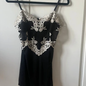 Svart spetsklänning från Intimissimi - Supersnygg svart spetslinne/klänning från Intimissimi med tunna axelband och vit broderad spets upptill och nedtill. 