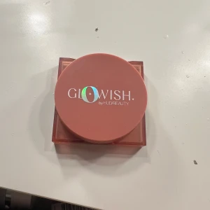 Glowish Cheeky Vegan Blush Healthy Peach - Glowish by Huda Beauty Cheeky Vegan Blush Powder i nyansen 01 Healthy Peach. Färgen är en fräsch persikoton med marmorerad finish. Kommer i en rund, persikofärgad plastförpackning med spegel i locket. Vegansk formula, perfekt för en naturlig glow.