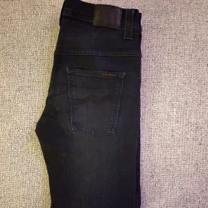 Mörkgrå jeans från Nudie Jeans -  Märke: Nudie jeans (Thin finn) 📏 Storlek: W32 L32 ✨ Skick: Mycket gott skick / Nästan som nya 🎯 Perfekta både till vardags och när du vill klä upp dig lite extra 📦 Snabb leverans – skickas samma dag! 💌 Har du frågor? Hör gärna av dig – svarar snabbt!
