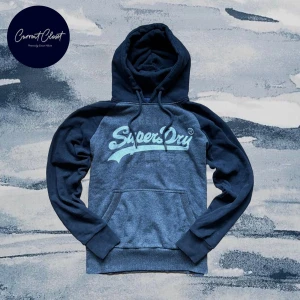 Mörkblå Superdry hoodie med tryck - Snygg mörkblå hoodie från Superdry med stort vitt logotryck på bröstet | Tröjan är grå men ser blå ut pga ljuset | Size M | Vintage och otroligt limiterad | Slutsåld | Pris kan diskuteras
