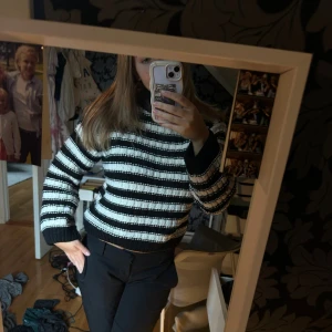 Randig svartvit stickad tröja - Säljer en stickad tröja med breda svarta och vita ränder. Tröjan har en hög hals, ribbade muddar och är långärmad. Den är lite boxig i modellen och passar perfekt för kyligare dagar. Superenkel att styla med både jeans och kostymbyxor.