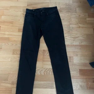 Svarta jeans 29/32 - Svarta jeans  och klassisk femficksdesign. Snygg  passform och midja med bälteshällor. Perfekta för dig som gillar en stilren look. Materialet är jeans och färgen är helsvart.