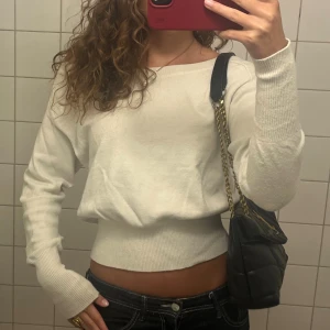 Vit stickad tröja med indragen midja - Snygg vit Offshoulder stickad tröja med lång ärm och bred ribbad mudd i midjan och vid ärmsluten. Står storlek xs men skulle säga s
