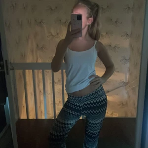 Mönstrade bootcut orrebyxor i blågrå vit - Säljer ett par snygga bootcut orrebyxor med gråblå vit zickzackmönster. Byxorna har låg midja och är i ett stretchigt, mjukt material som sitter skönt på kroppen. Perfekta för dig som vill sticka ut med en cool look från tessie 