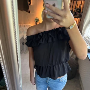 Svart offshoulder volangtopp - Säljer en svart offshoulder topp med volangdetaljer! Storlek M 