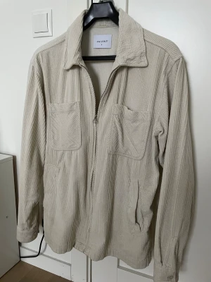 Beige manchester overshirt från Vailent - Säljer en beige overshirt från Vailent i mjuk manchester med dragkedja framtill, två bröstfickor och klassisk krage. Jackan har långärmade ärmar med knapp vid mudden och en loose passform som är chill och enkel att styla. Modellen är 188cm och 69kg. Bara att skriva om du har några frågor! 😇👏🙌