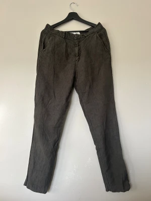 Grå linnebyxor från A Day's March - Snygga grå linnebyxor från A Day's March med rak passform och klassisk midja. Byxorna har sidfickor, bakfickor med knapp och stängs med knapp och dragkedja fram. Perfekta för en chill och stilren look. 