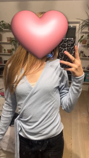 Ljusblå omlottopp från 157 - Säljer en ljusblå omlottopp från 157 i ribbad bomull. Toppen har lång ärm, v-ringning och knyt i sidan för en snygg passform. Perfekt att styla med jeans eller kjol för en chill och trendig look. Helt nya då jag säljer eftersom jag inte använder den❤️