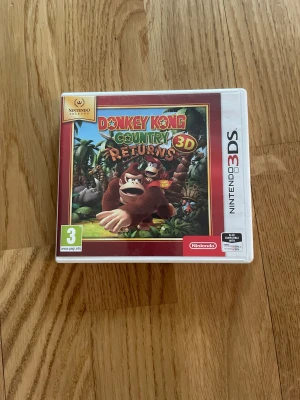 Donkey Kong Country Returns 3D - Donkey Kong Country Returns 3D till Nintendo 3DS, komplett med originalkartong, manual och spelkassett. Spelet och förpackningen är i mycket fint skick utan synligt slitage. Perfekt för samlare eller fans av klassiska plattformsspel.